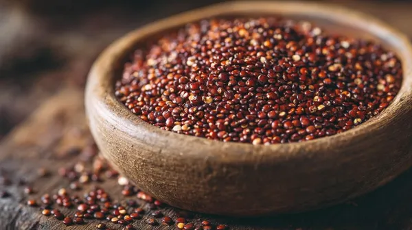Rote Quinoa-Körner in Holzschale - nussig-aromatische Quinoa-Sorte mit charakteristischer roter Farbe